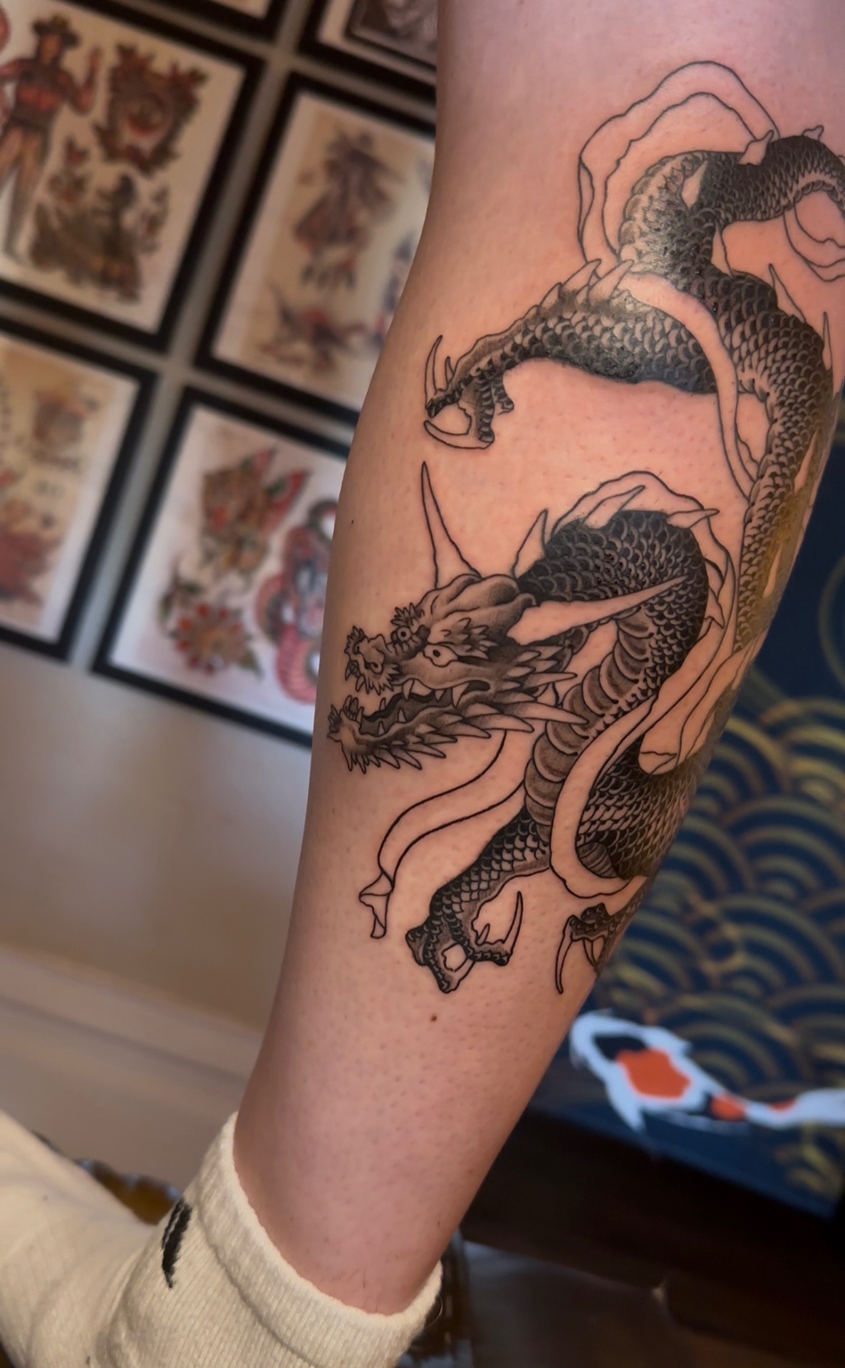 Black and grey Japanese dragon tattoo coiling down a lower leg