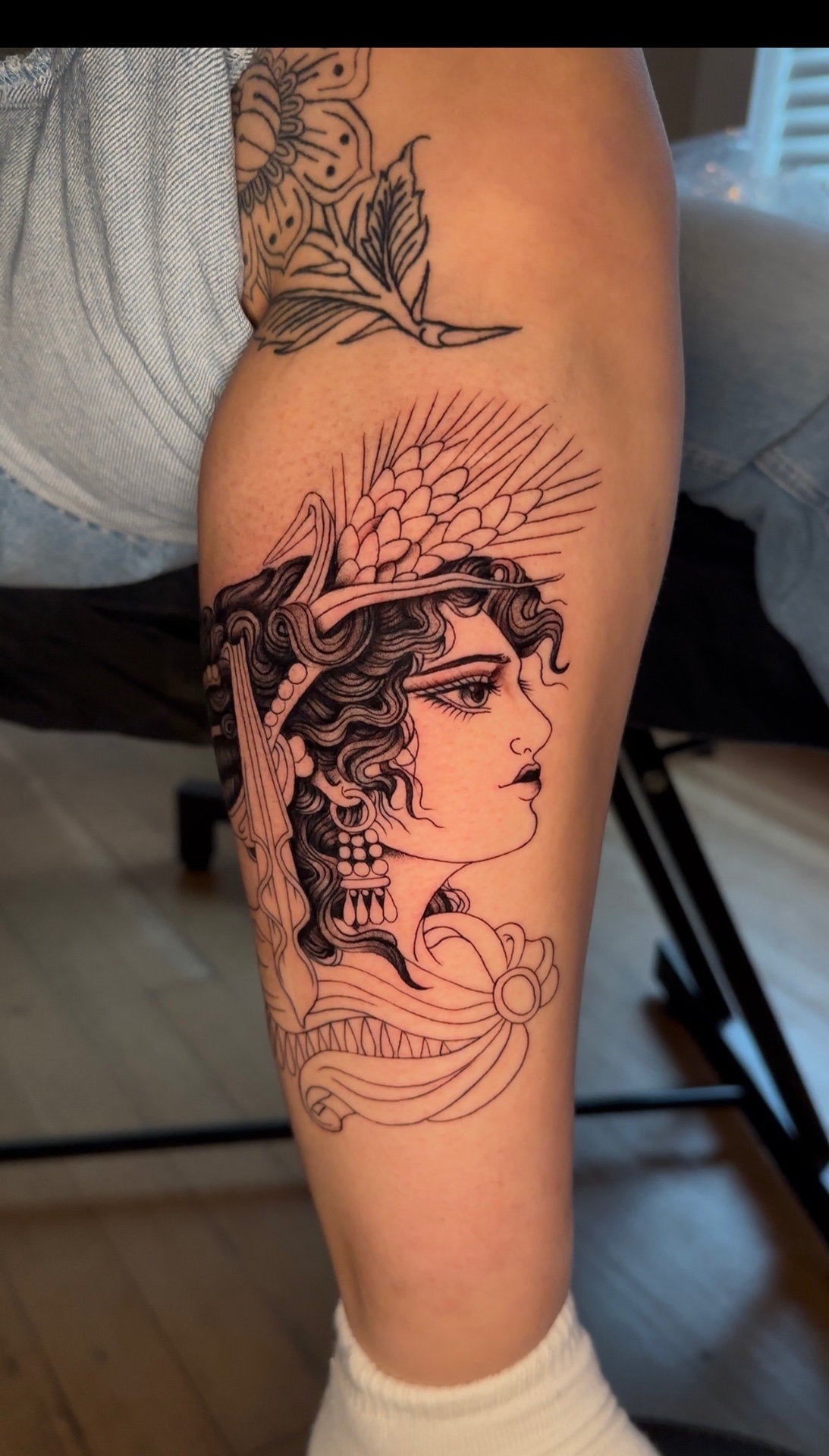 Fine-line blackwork tattoo of a classical bust wearing a crown of wheat, on a calf